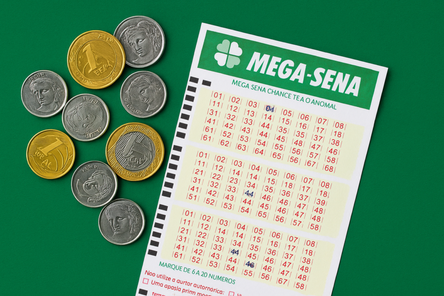 Bilhete da Mega-Sena ao lado de moedas brasileiras