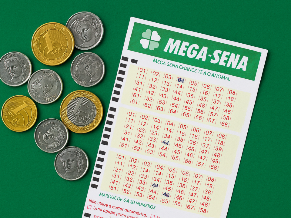 Bilhete da Mega-Sena ao lado de moedas brasileiras